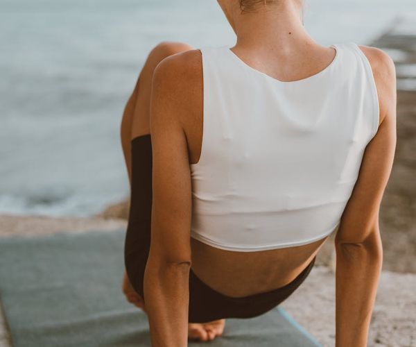 Person stretching gently outdoors during sunrise.